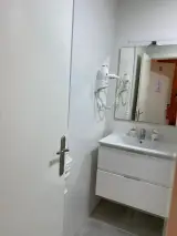Dos camas individuales reflejadas en un espejo frente a una pared de madera en la habitación